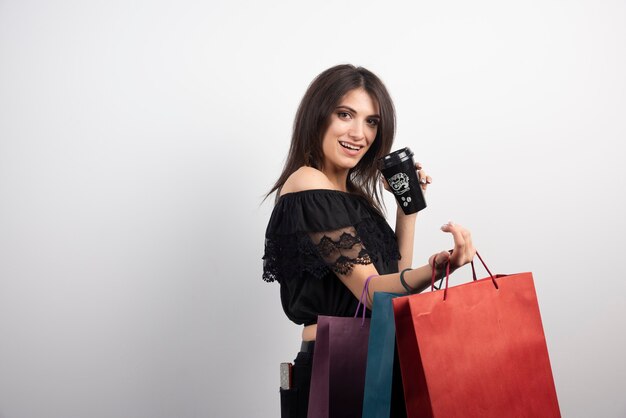 Mujer morena con bolsas de la compra y taza de café.