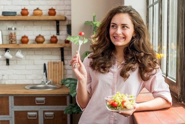 Mujer morena comiendo una ensalada