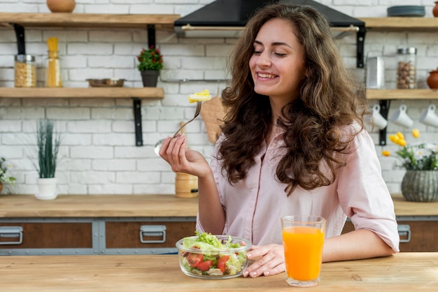 Mujer morena comiendo una ensalada