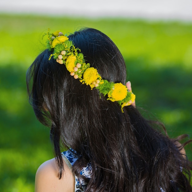 Mujer morena con corona de flores amarillas en la cabeza.