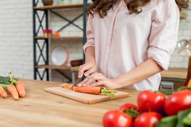 Mujer morena cortando zanahorias