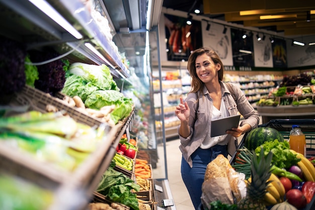 Mujer morena disfruta de comprar comida en el supermercado