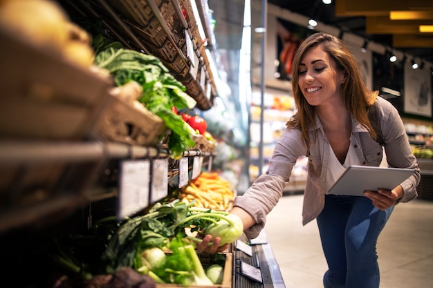Mujer morena disfruta eligiendo comida en el supermercado