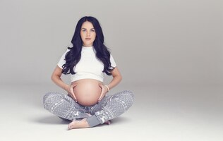 Foto gratuita mujer morena embarazada sentada con las piernas cruzadas.