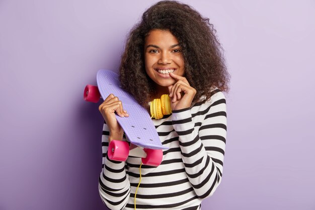 Mujer morena encantadora patinadora posando con tabla larga