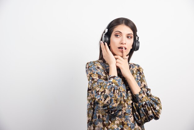 Mujer morena escuchando música en auriculares.