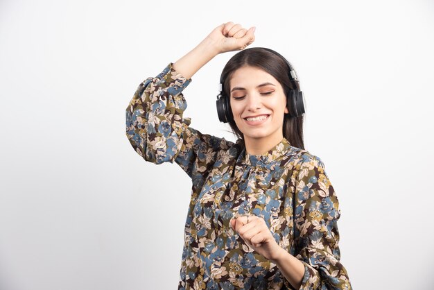 Mujer morena escuchando música y bailando con expresión feliz.