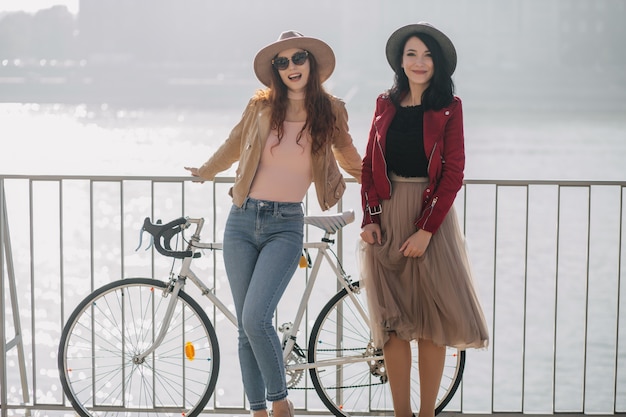 Mujer morena en falda larga vintage de pie con un amigo en el puente