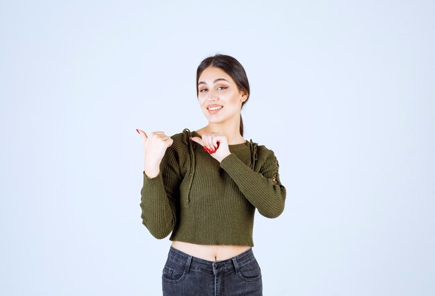 mujer morena felizmente apuntando a algo sobre fondo blanco.