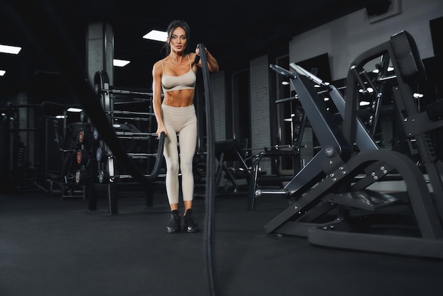 Mujer morena en forma haciendo entrenamiento de cuerda de batalla