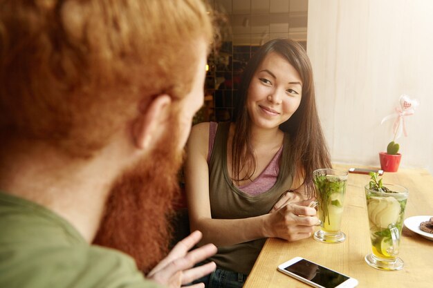 Mujer morena y hombre jengibre sentado en el café