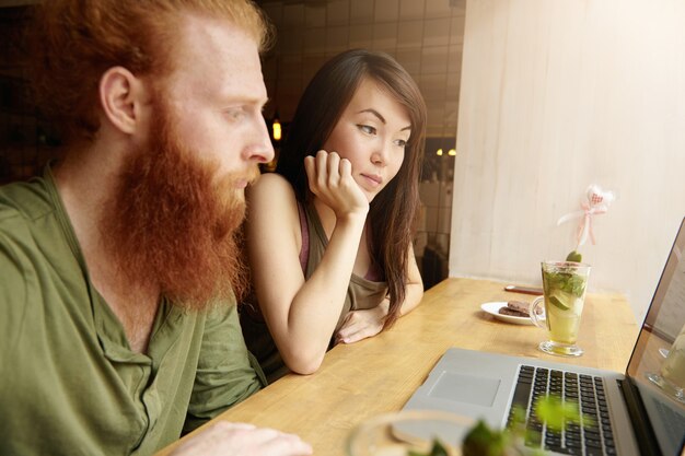 Mujer morena y hombre jengibre sentado en el café