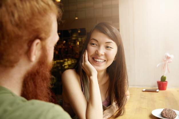 Mujer morena y hombre jengibre sentado en el café