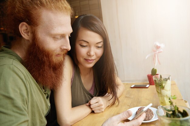 Mujer morena y hombre jengibre sentado en el café