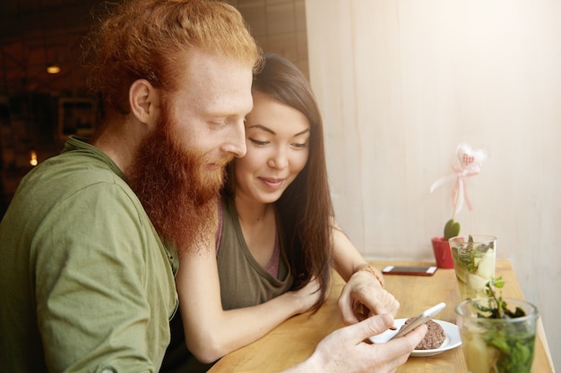 Mujer morena y hombre jengibre sentado en el café