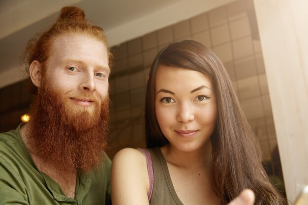 Mujer morena y hombre jengibre sentado en el café