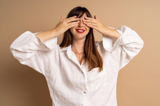 Mujer morena de moda cierra los ojos con las manos y piensa en un estilo minimalista