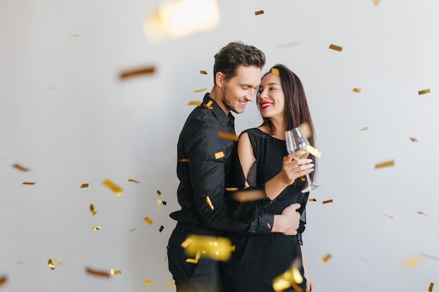 Mujer morena de pelo largo mira la cara del marido con ternura, disfrutando de la fiesta de cumpleaños