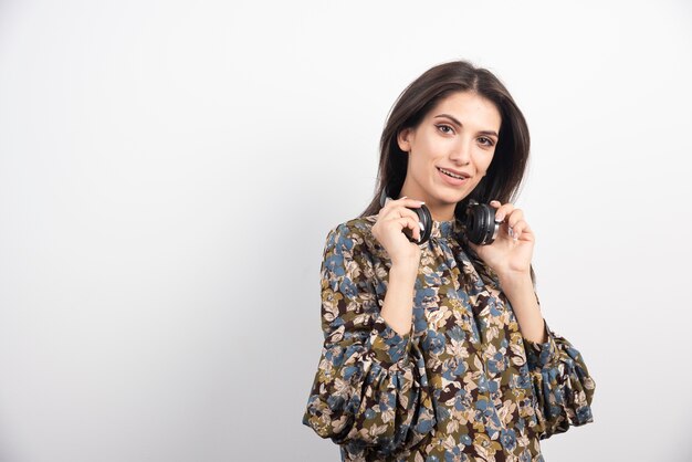 Mujer morena posando con auriculares sobre fondo blanco.