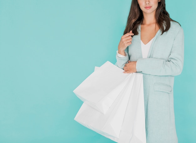 Mujer morena que sostiene bolsos de compras blancos