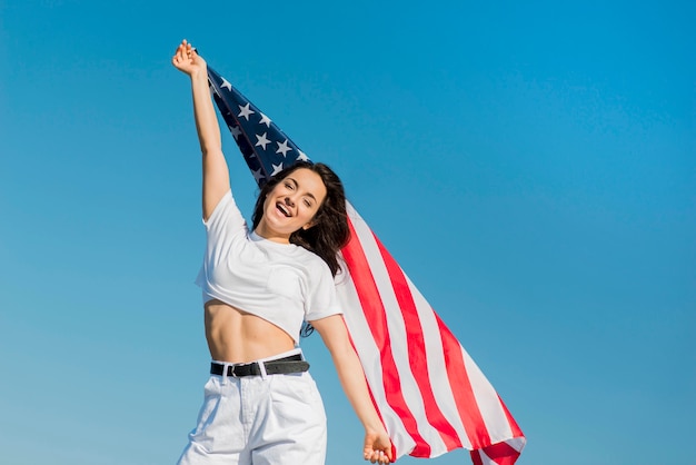 Mujer morena en ropa blanca con gran bandera de Estados Unidos