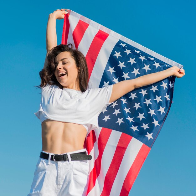 Mujer morena en ropa blanca con gran bandera de Estados Unidos