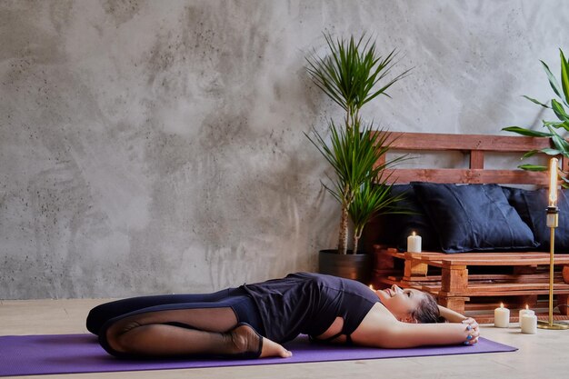 Mujer morena sexy haciendo yoga, Pilates en un baño con palmeras verdes.