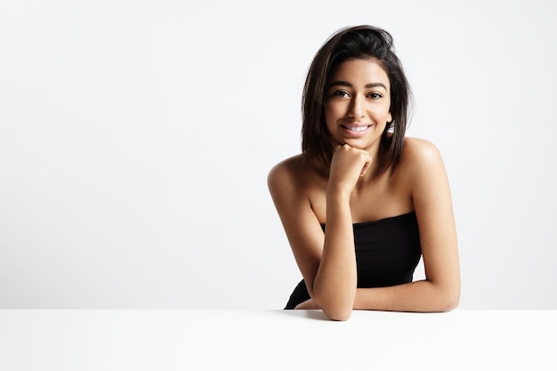 Foto gratuita mujer morena sonriente con una piel sana y un estudio de cabello para disparar un espacio en blanco