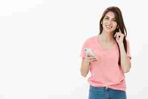 Foto gratuita mujer morena sonriente posando en el estudio con su teléfono y auriculares