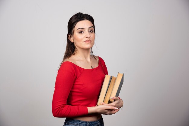 mujer morena sonriente sosteniendo libros en las manos.