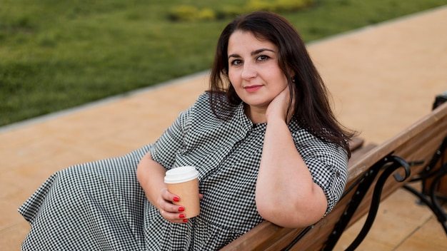 Foto gratuita mujer morena sonriente sosteniendo una taza de café al aire libre