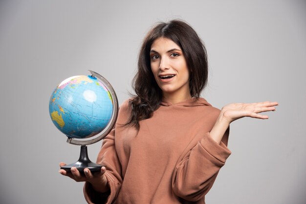 Mujer morena sosteniendo globo en gris