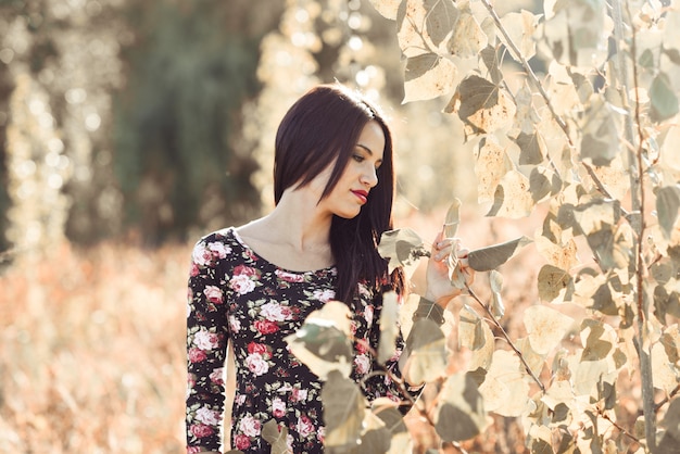 Mujer morena tocando algunas hojas en el campo