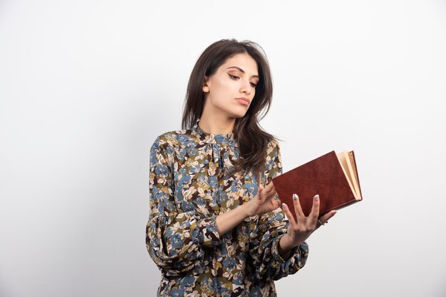 Mujer morena tratando de leer un libro.