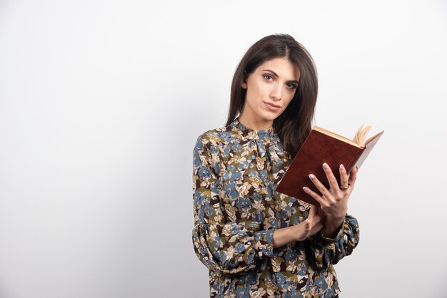 Mujer morena tratando de leer un libro.