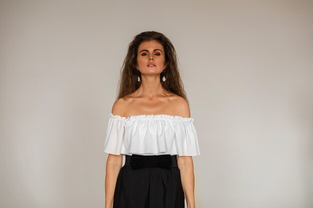 Mujer morena vestida con blusa blanca y falda negra