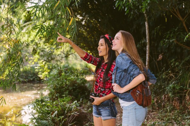 Mujer mostrando algo a su amiga en el bosque