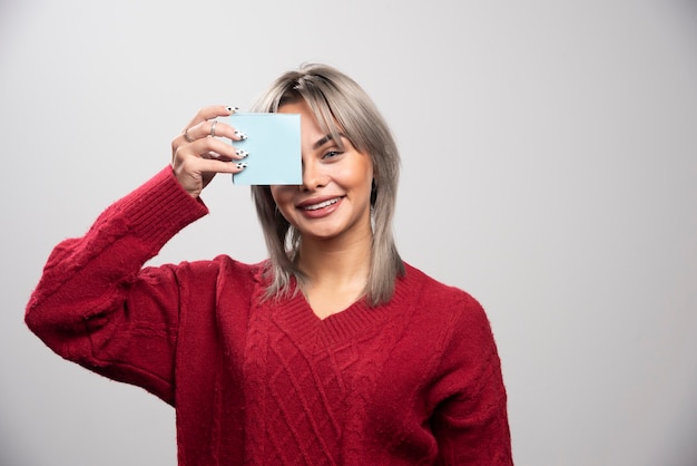 Foto gratuita mujer mostrando bloc de notas sobre fondo gris.