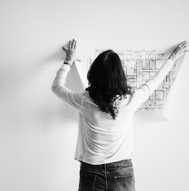 Foto gratuito mujer mostrando edificio plano en la pared