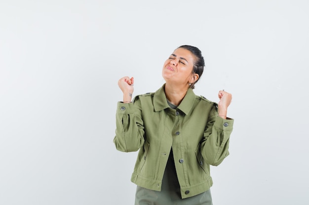 mujer mostrando gesto ganador en chaqueta, camiseta y con suerte.