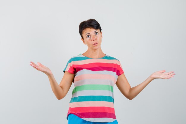 Mujer mostrando gesto de impotencia en camiseta a rayas y mirando confundido.