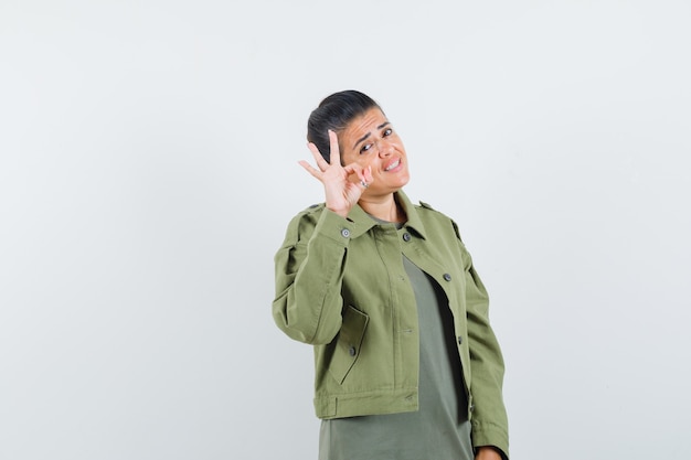 mujer mostrando gesto ok en chaqueta, camiseta y mirando confiado.