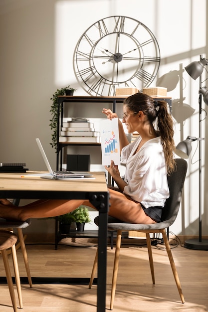 Foto gratuita mujer mostrando el gráfico a la computadora portátil