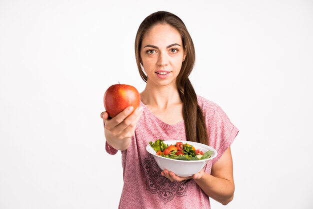 Mujer mostrando una manzana y mirando a cámara