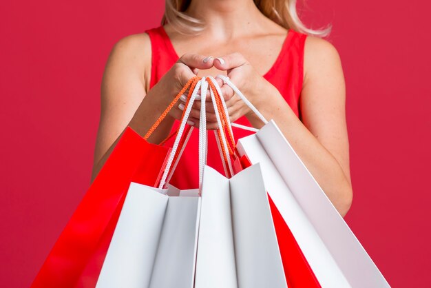 Mujer mostrando un montón de bolsas de la compra después de la juerga de compras