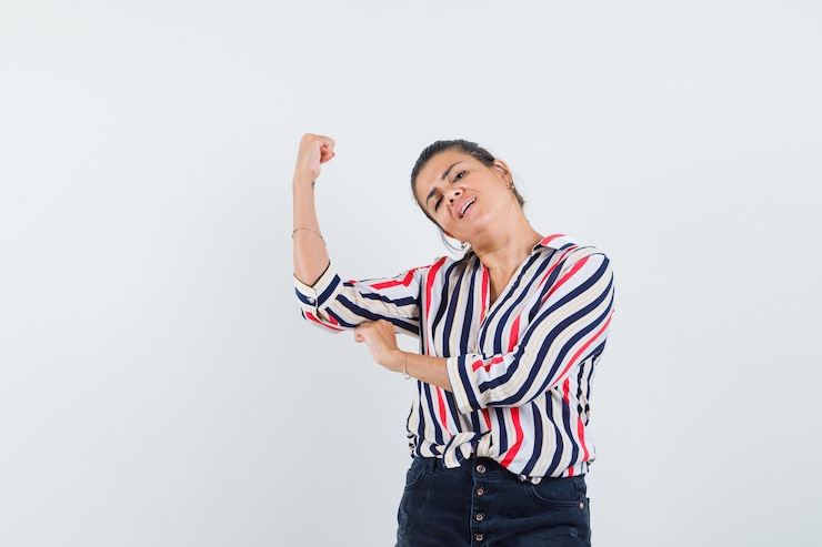 Foto gratuito mujer mostrando los músculos del brazo en camisa, falda y luciendo orgullosa.
