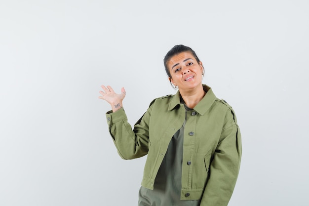 mujer mostrando palma en chaqueta, camiseta y mirando confiado