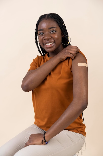 Mujer mostrando pegatina en el brazo después de recibir una vacuna