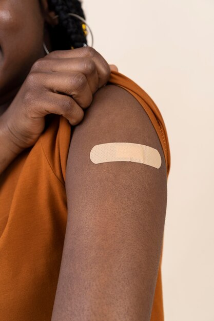 Mujer mostrando pegatina en el brazo después de recibir una vacuna