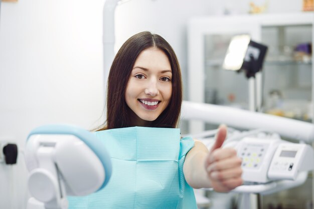 Mujer mostrando los pulgares para arriba en una recepción en el dentista